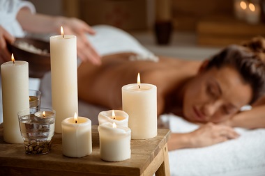 Young beautiful girl relaxing in spa salon. Focus on candles.